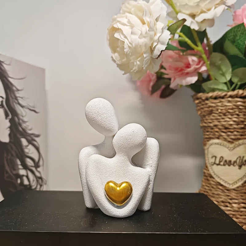 Decorative sculpture of two figures embracing with a gold heart, placed on a surface with flowers in the background.