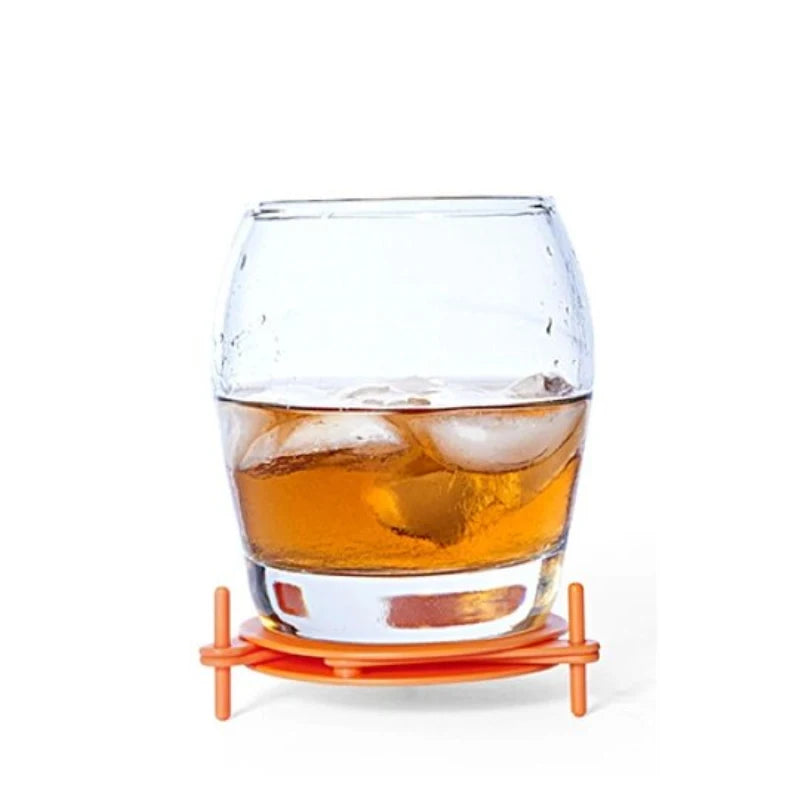 Clear glass with orange liquid on an orange coaster against a white background