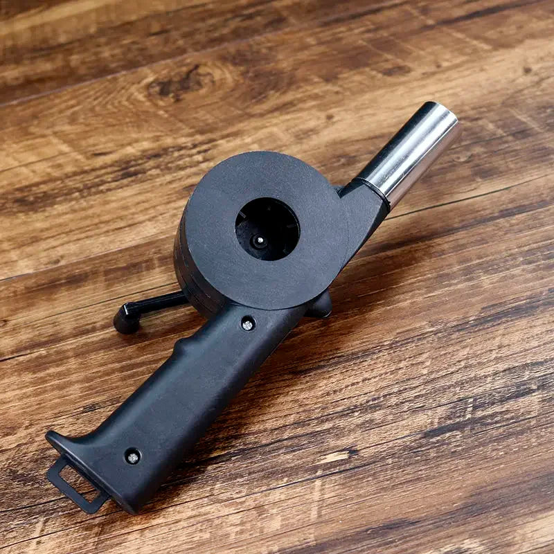 Black handheld tool with a metallic nozzle on a wooden surface