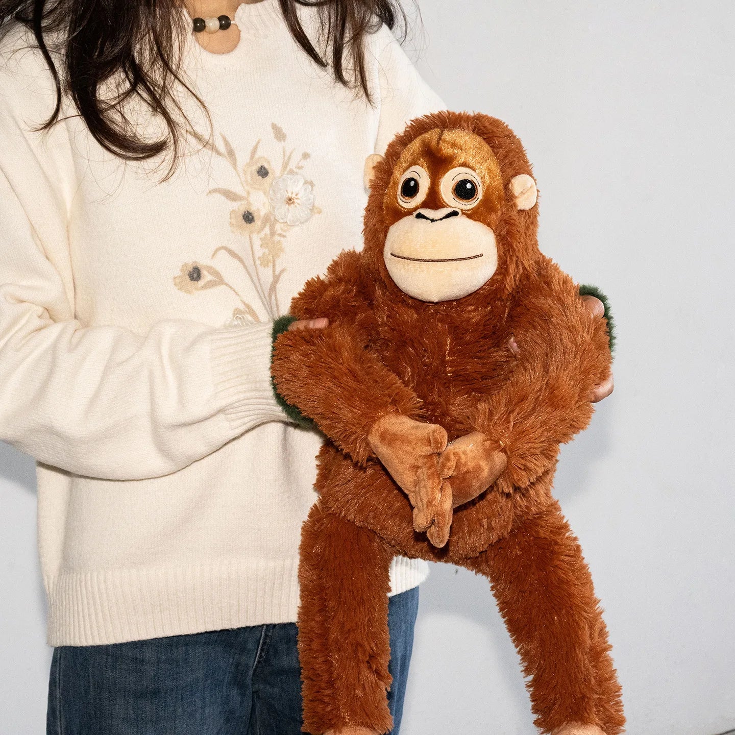 Person holding a plush monkey toy against a plain background