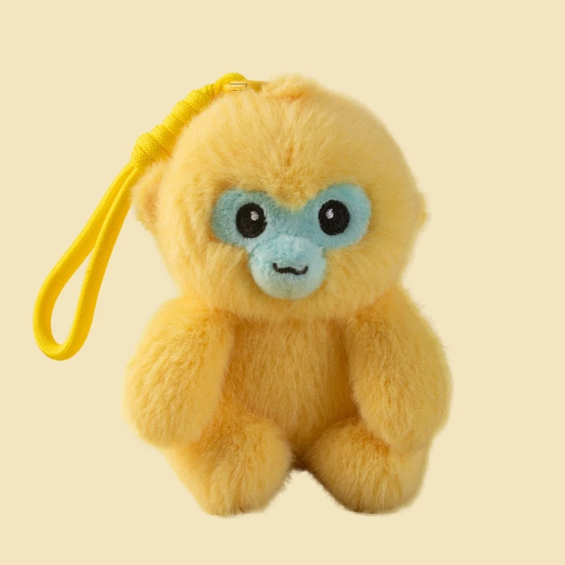 Plush monkey toy with blue face and yellow strap on a beige background
