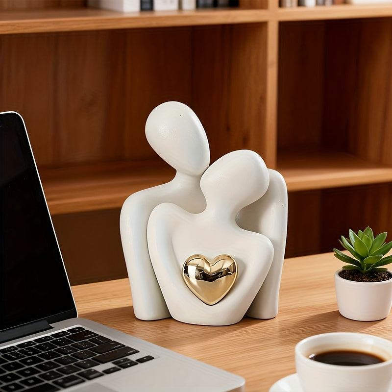 White ceramic sculpture of a couple with a gold heart on a desk with a laptop and coffee.